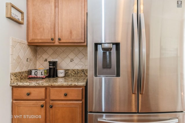 kitchen featuring stainless steel fridge with ice dispenser, backsplash, light stone counters, and brown cabinets