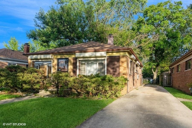 15427 Winchester Ave, Harvey, IL 60426 - bungalow-style home featuring a chimney, brick siding, a front lawn, and concrete driveway