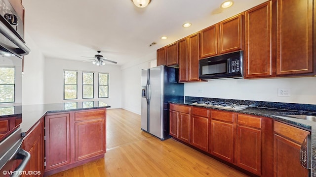 kitchen featuring stainless steel refrigerator with ice dispenser, black microwave, gas stovetop, light wood finished floors, and a ceiling fan