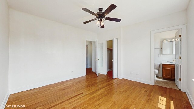 unfurnished bedroom with light wood finished floors, baseboards, a closet, connected bathroom, and a sink
