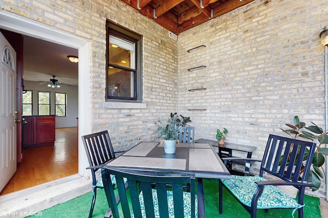 dining room with brick wall, wood finished floors, ceiling fan, wood ceiling, and beamed ceiling