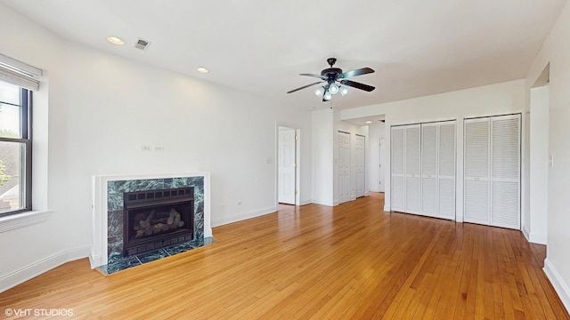 unfurnished living room with ceiling fan, light wood-style flooring, a premium fireplace, baseboards, and recessed lighting