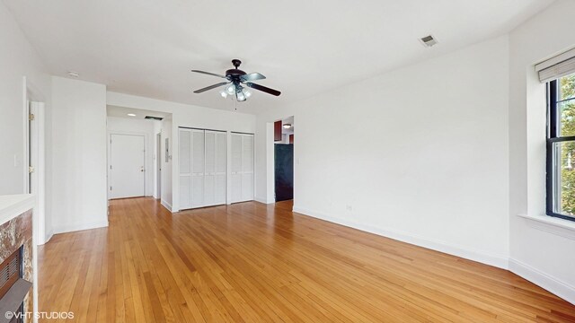 unfurnished bedroom with a fireplace, light wood-style floors, baseboards, and ceiling fan
