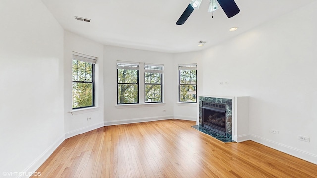 unfurnished living room with wood-type flooring, baseboards, a ceiling fan, and a fireplace