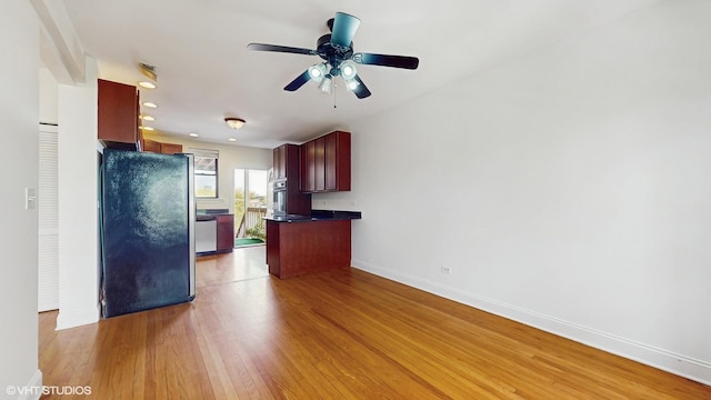 kitchen with stainless steel appliances, dark countertops, baseboards, light wood finished floors, and ceiling fan