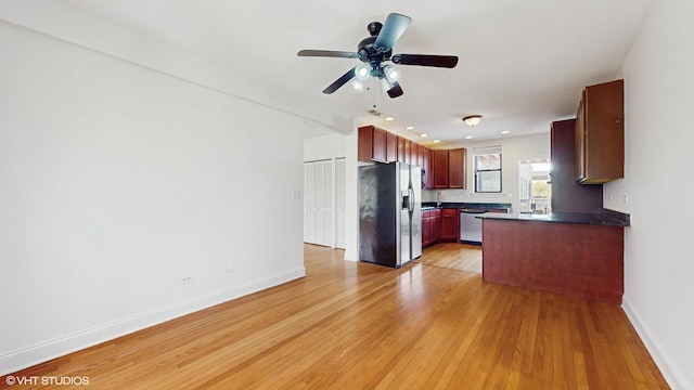 kitchen featuring appliances with stainless steel finishes, dark countertops, light wood-style flooring, reddish brown cabinets, and baseboards