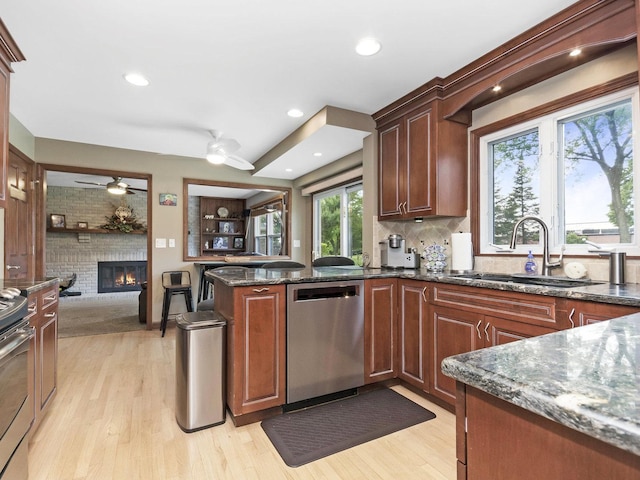 848 Braintree Ln, Bartlett, IL 60103 - kitchen with appliances with stainless steel finishes, ceiling fan, a sink, a fireplace, and dark stone counters