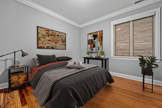 bedroom featuring crown molding, wood finished floors, and baseboards