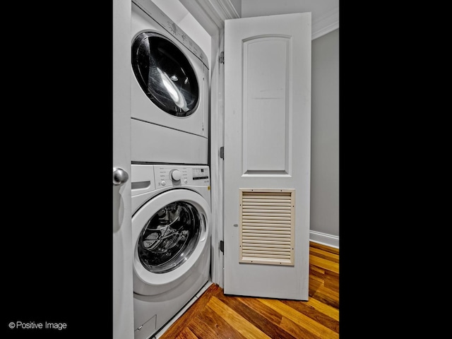 laundry room featuring laundry area, wood finished floors, and stacked washer / drying machine
