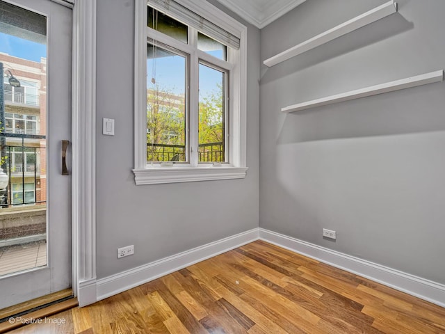 empty room featuring baseboards, ornamental molding, and wood finished floors