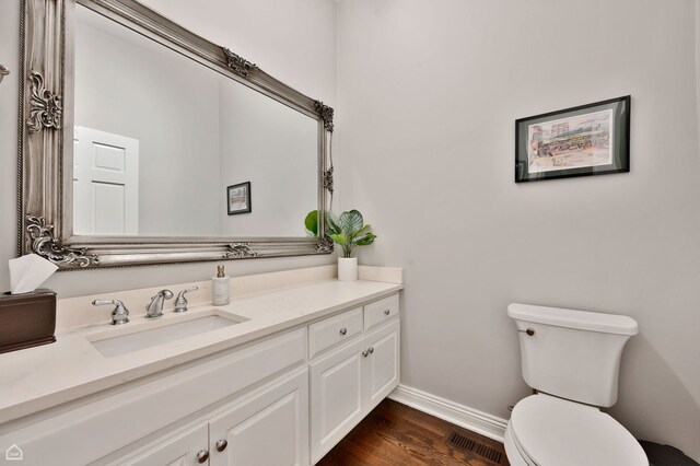 bathroom featuring baseboards, toilet, wood finished floors, and vanity