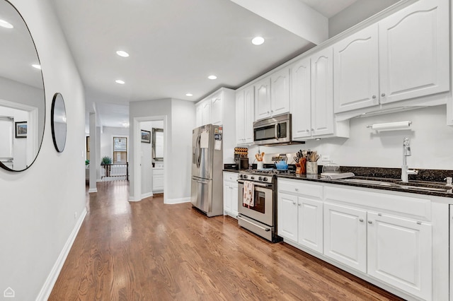 kitchen featuring stainless steel appliances, a sink, light wood-type flooring, recessed lighting, and white cabinetry
