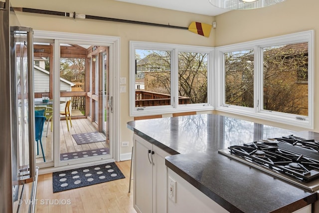 6927 N Oleander Ave, Chicago, IL 60631 - kitchen featuring light wood finished floors, dark countertops, white cabinets, and stovetop with downdraft