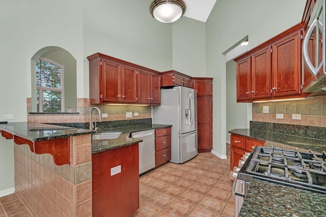 472 Linden Cir, Beecher, IL 60401 - kitchen with appliances with stainless steel finishes, a sink, a peninsula, dark stone counters, and a high ceiling