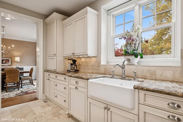 3324 Lakeside Ave, Northbrook, IL 60062 - kitchen with a sink, light stone countertops, a chandelier, backsplash, and white cabinetry