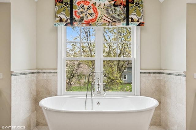 full bathroom with tile walls, a wainscoted wall, and a soaking tub