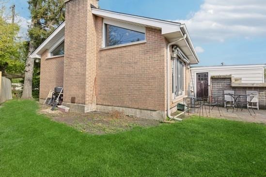 2104 S River Rd, Des Plaines, IL 60018 - view of side of home with a chimney, a patio, brick siding, and a lawn
