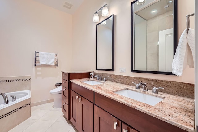 full bath with tile patterned floors, double vanity, a relaxing tiled tub, and toilet