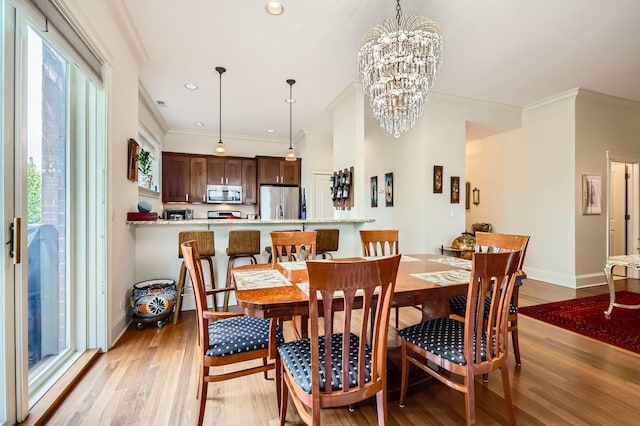 dining space featuring plenty of natural light, light wood-style floors, crown molding, a chandelier, and baseboards