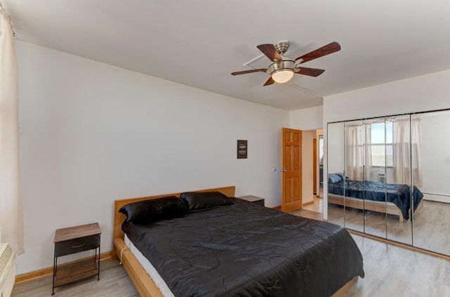 bedroom featuring light wood finished floors, ceiling fan, a baseboard radiator, and baseboards