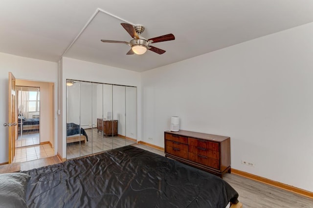 bedroom featuring baseboards, light wood-type flooring, a ceiling fan, and a closet