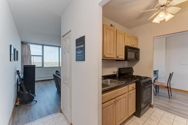 kitchen featuring black appliances, light brown cabinetry, dark countertops, baseboard heating, and a sink
