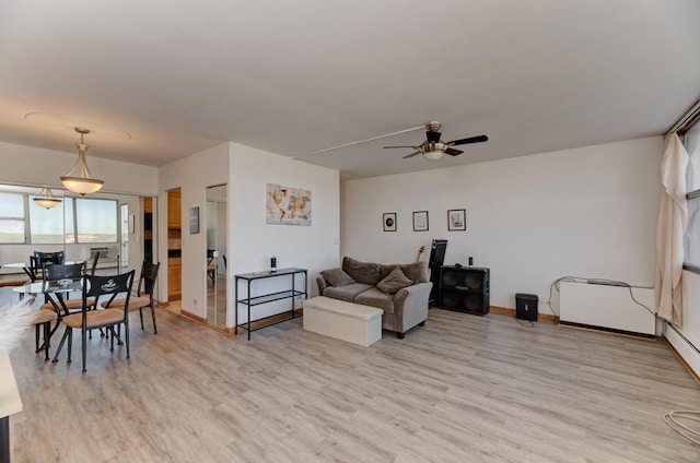 living area with light wood-style flooring, ceiling fan, and baseboards