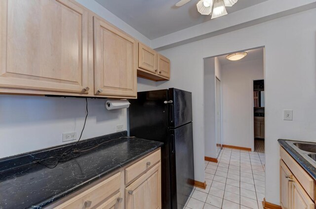 kitchen with light brown cabinets, freestanding refrigerator, light tile patterned flooring, ceiling fan, and baseboards