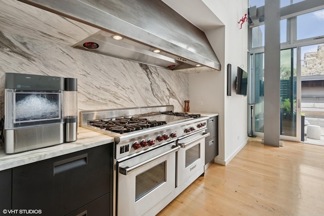 kitchen with range with two ovens, baseboards, dark cabinetry, light wood finished floors, and decorative backsplash
