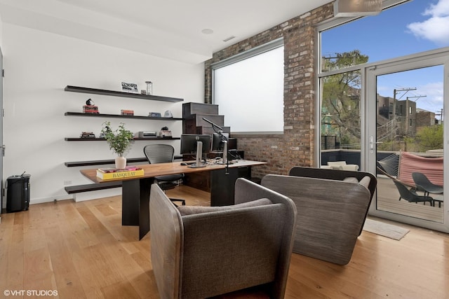 home office featuring brick wall and light wood-style flooring