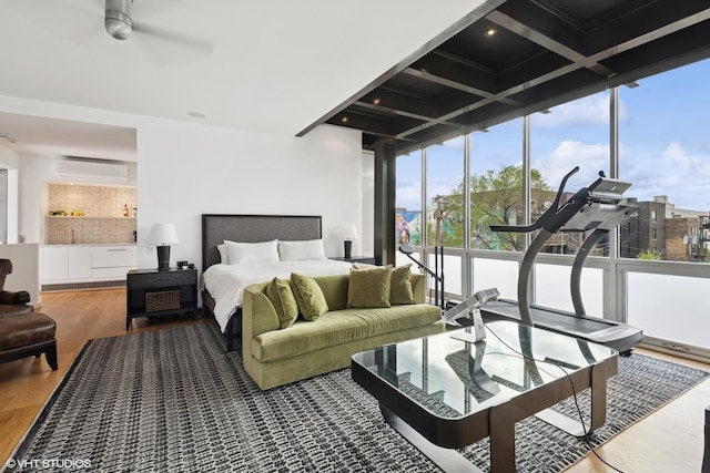 bedroom with expansive windows, wood finished floors, beamed ceiling, and an AC wall unit