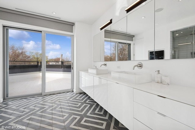bathroom featuring recessed lighting, walk in shower, double vanity, and a sink