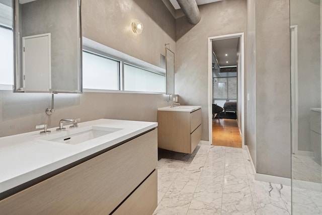 ensuite bathroom featuring ensuite bathroom, marble finish floor, two vanities, and a sink