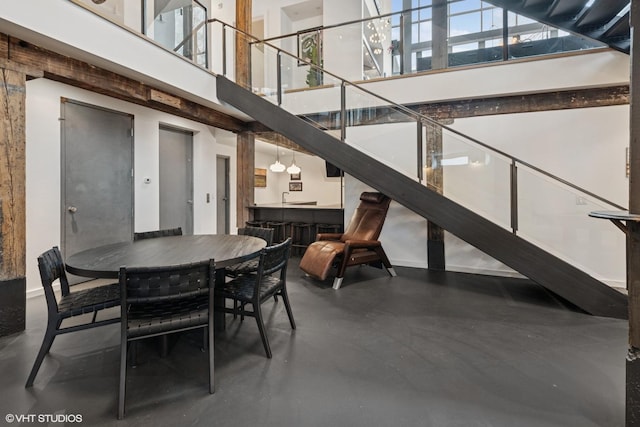 dining area featuring finished concrete floors and a towering ceiling