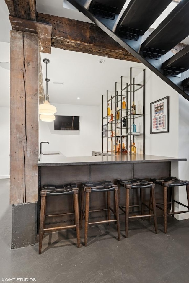 bar with decorative light fixtures, concrete flooring, a sink, and bar area