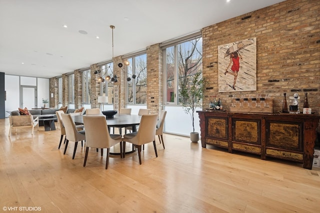dining room featuring brick wall, hardwood / wood-style floors, and floor to ceiling windows