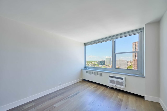 555 W Cornelia Ave Unit 1906, Chicago, IL 60657 - unfurnished room with baseboards, wood finished floors, radiator heating unit, a wall mounted air conditioner, and a view of city