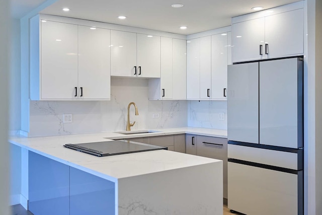 555 W Cornelia Ave Unit 1906, Chicago, IL 60657 - kitchen featuring freestanding refrigerator, a sink, a peninsula, light stone countertops, and backsplash