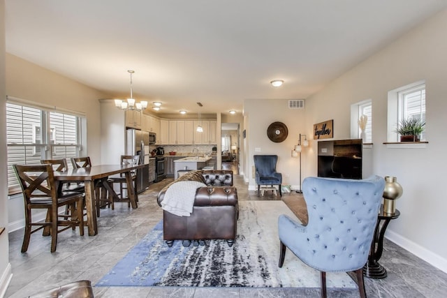 living area featuring baseboards and a chandelier