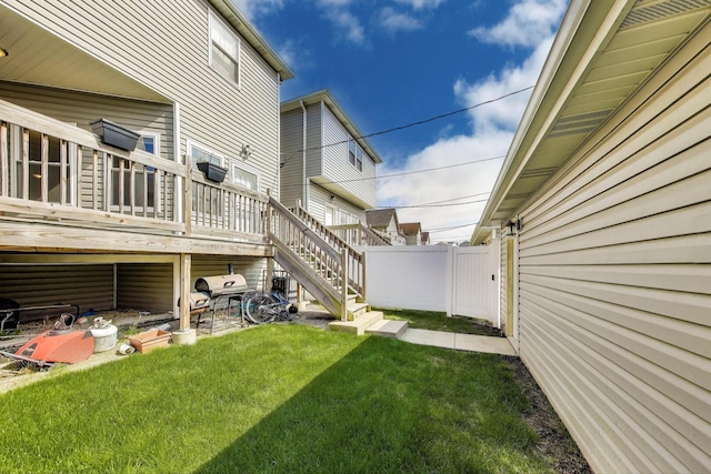 view of grassy yard with stairs and a deck