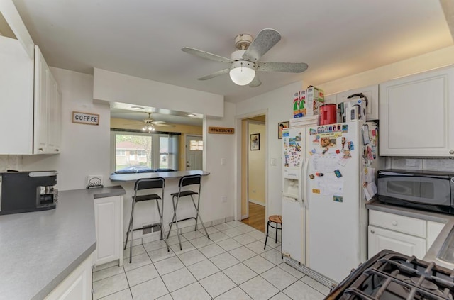 1431 N Hillside Ave, Berkeley, IL 60163 - kitchen with ceiling fan, black microwave, white cabinetry, and white refrigerator with ice dispenser