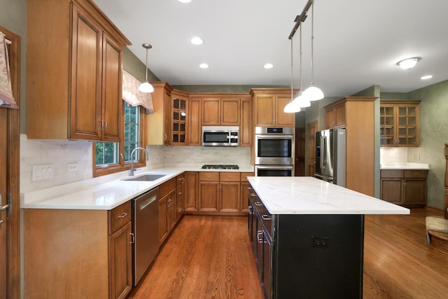 28W624 Berkshire Rd, West Chicago, IL 60185 - kitchen with stainless steel appliances, a sink, brown cabinetry, wood finished floors, and a kitchen island