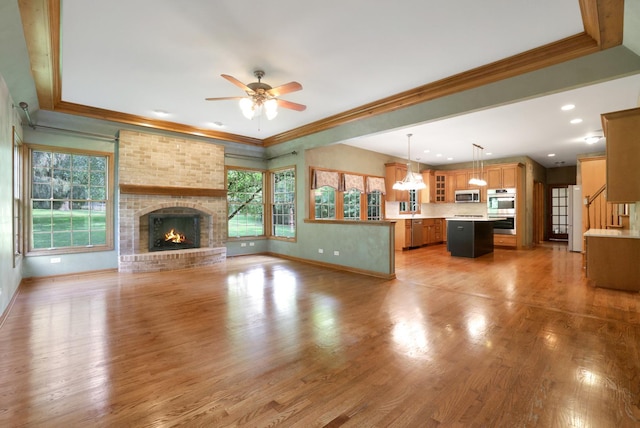 28W624 Berkshire Rd, West Chicago, IL 60185 - unfurnished living room with a ceiling fan, baseboards, a brick fireplace, crown molding, and light wood-type flooring