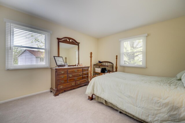 bedroom with multiple windows, light colored carpet, and baseboards