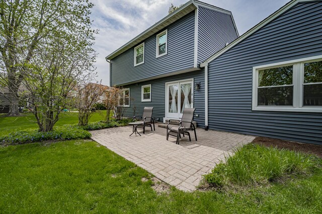 back of house with a patio and a lawn