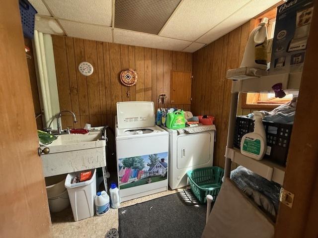 laundry room featuring washer and dryer and wood walls