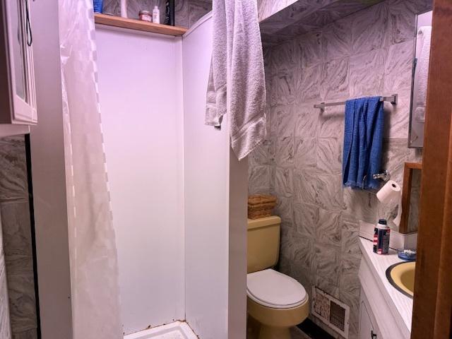 bathroom featuring toilet, vanity, and a shower with curtain