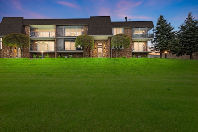 view of front of home with brick siding and a lawn