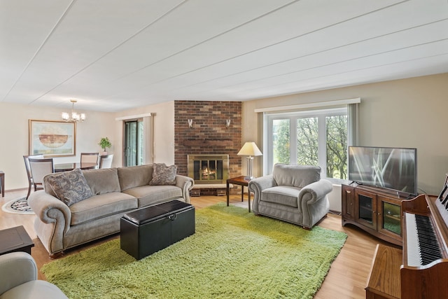 living area featuring light wood finished floors, an inviting chandelier, and a fireplace