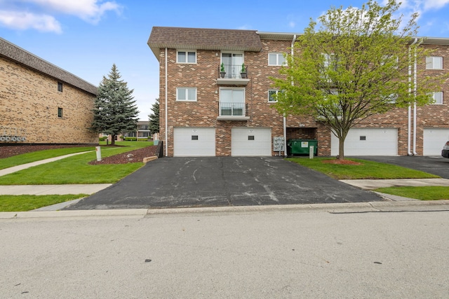 townhome / multi-family property featuring aphalt driveway, a garage, brick siding, and a front yard